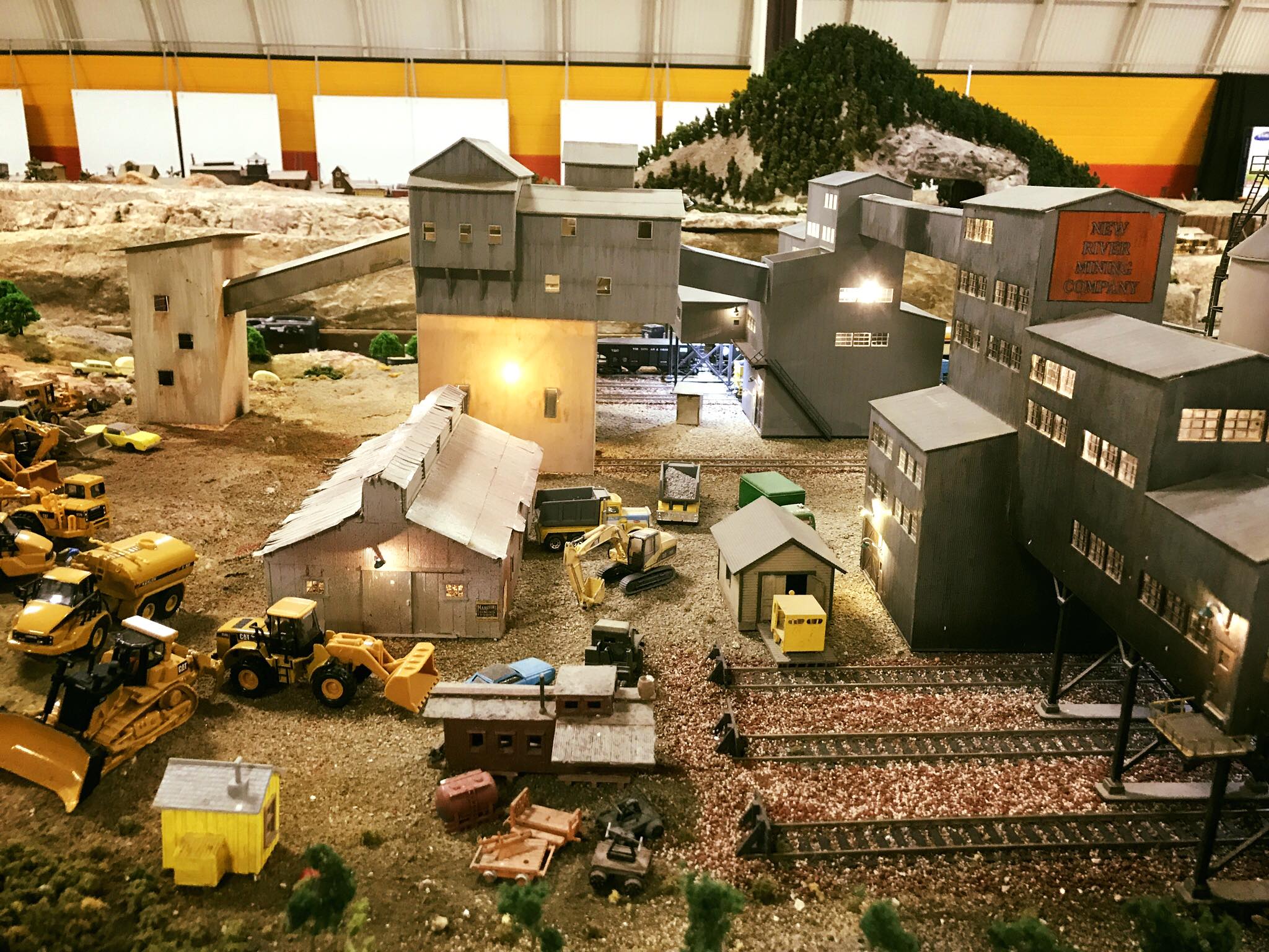 Detailed model of a mining facility, featuring various buildings, machinery, and railroad tracks, showcasing a miniature industrial scene.